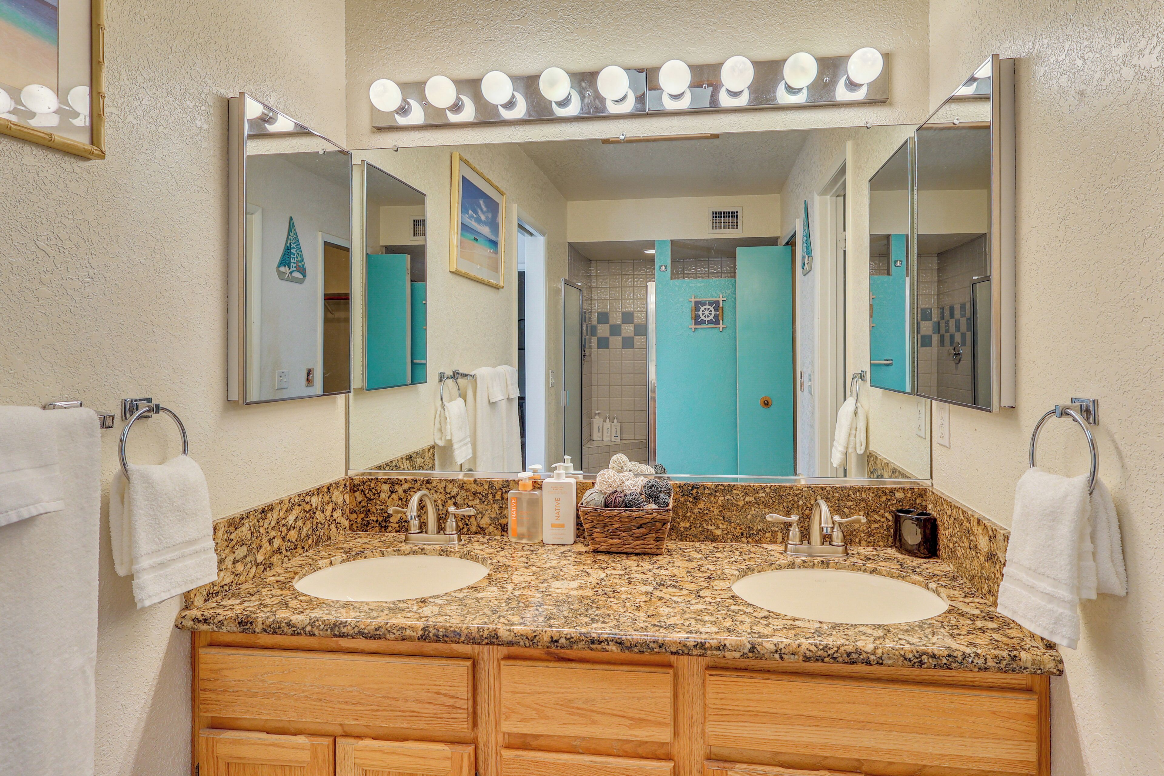A bathroom with two sinks, a large mirror, and a vanity with drawers.