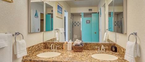 A bathroom with two sinks, a large mirror, and a vanity with drawers.