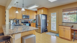 A kitchen with granite countertops, stainless steel appliances, wooden cabinets, and a view through a window. - Quiet Home w/ Spacious Yard in Lake Havasu City (Lake Havasu City)