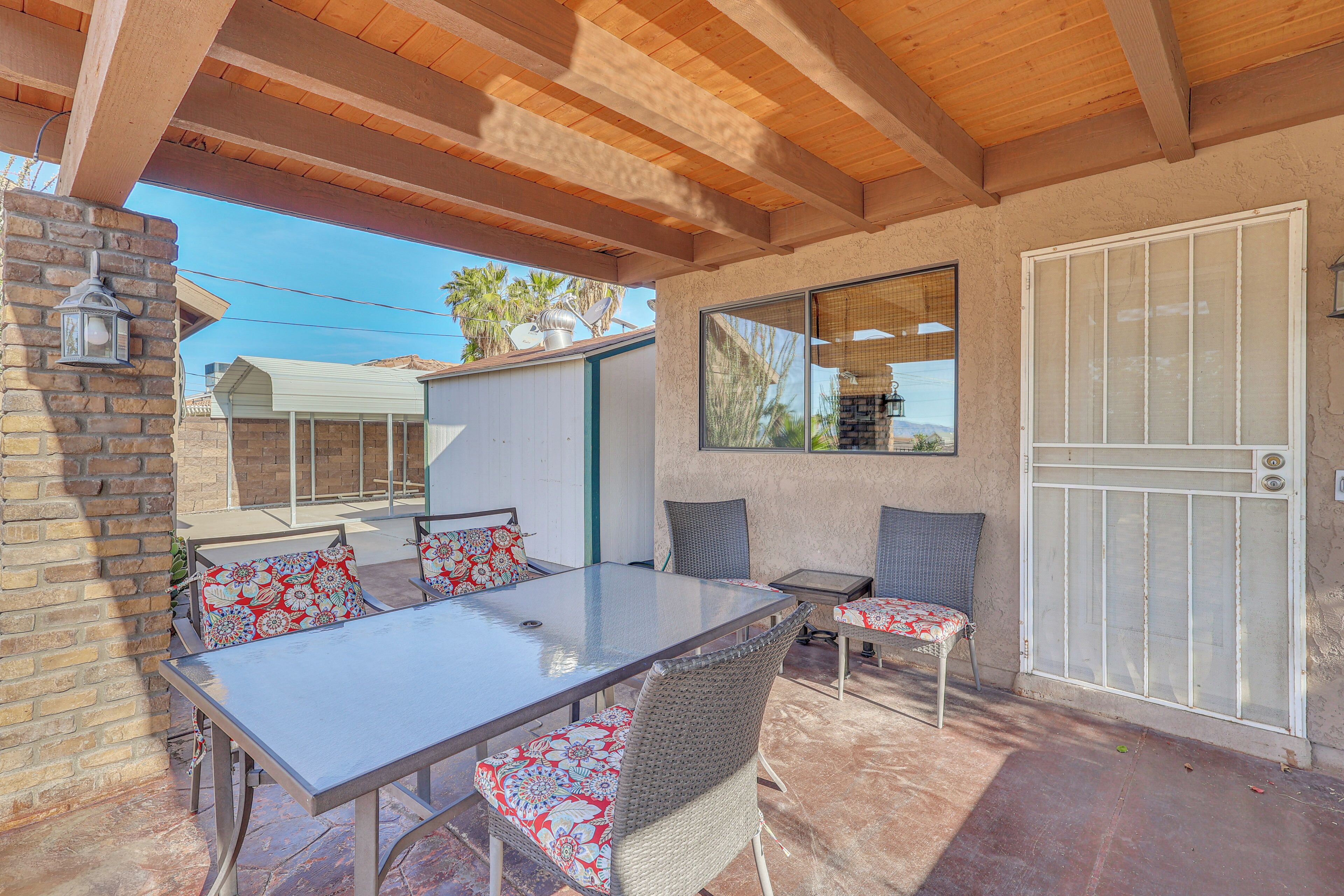 A covered patio with a table and chairs, a brick wall, and a door.