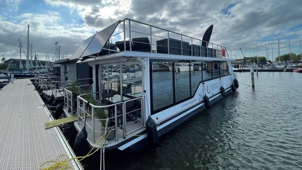 Un barco blanco con cubierta superior protegida, cerramiento de vidrio y una dirección web en el costado.