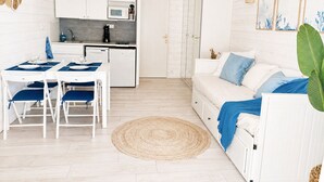 Un espacio habitable compacto con kitchenette, comedor y sofá con vista.