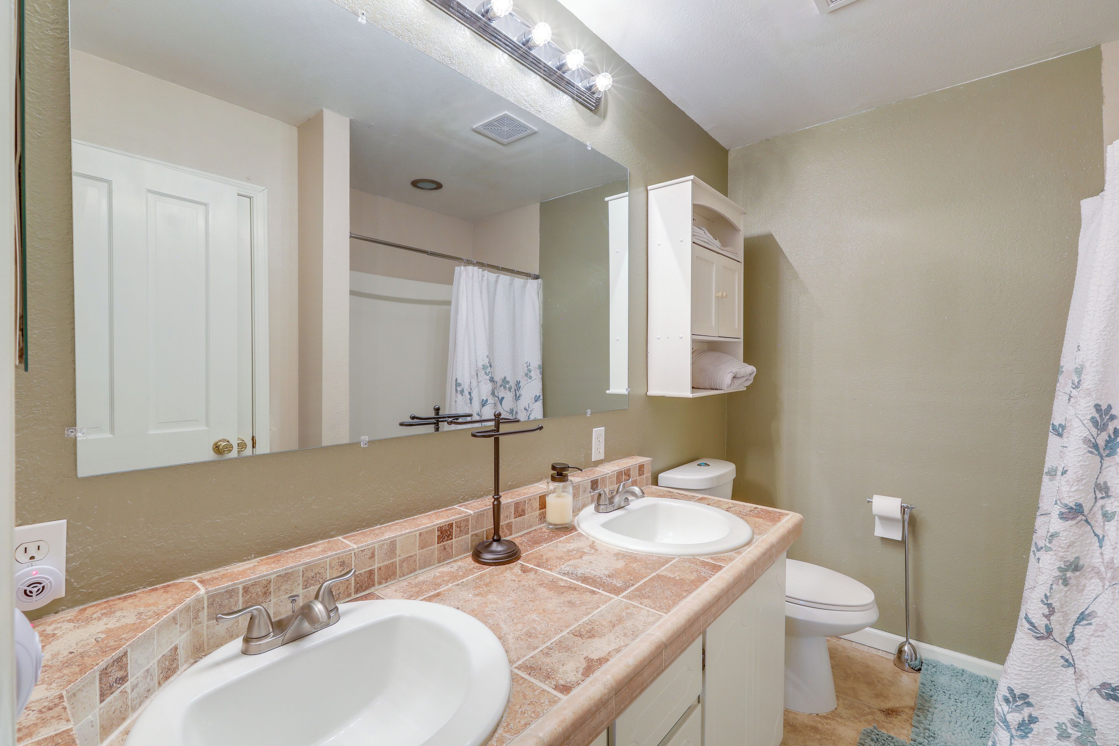 A bathroom with two sinks, a toilet, a mirror, and a shower curtain.