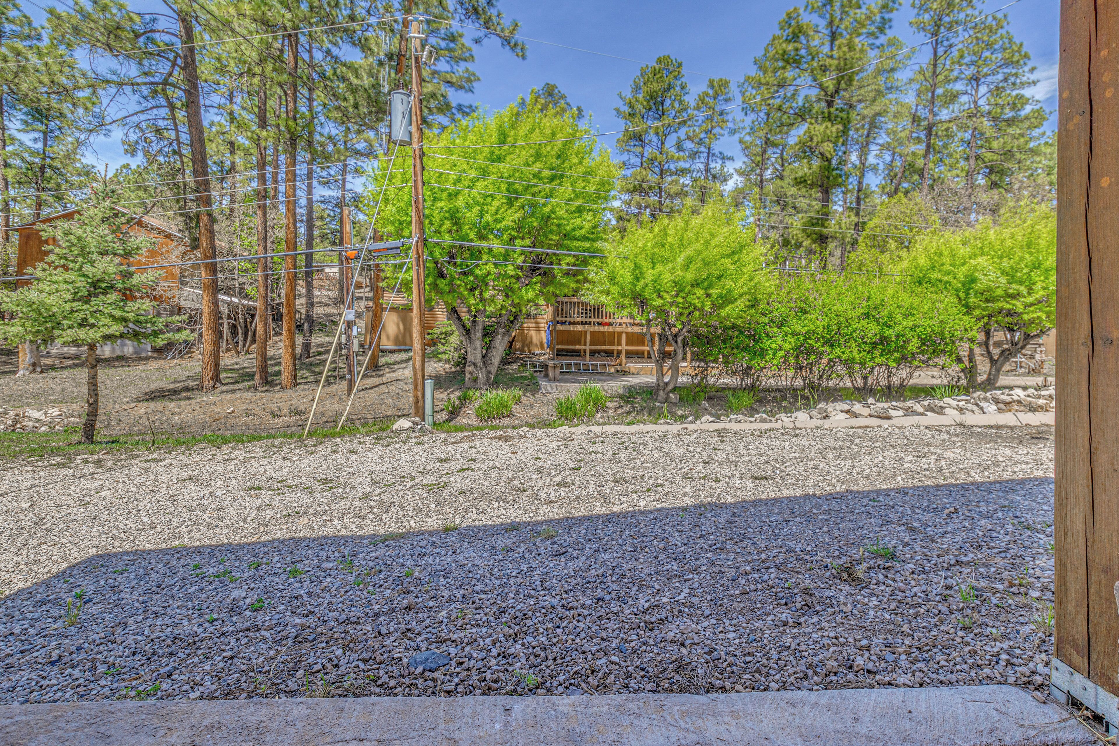 A residential area with a gravel driveway, wooden fence, and a wooden building with a porch.
