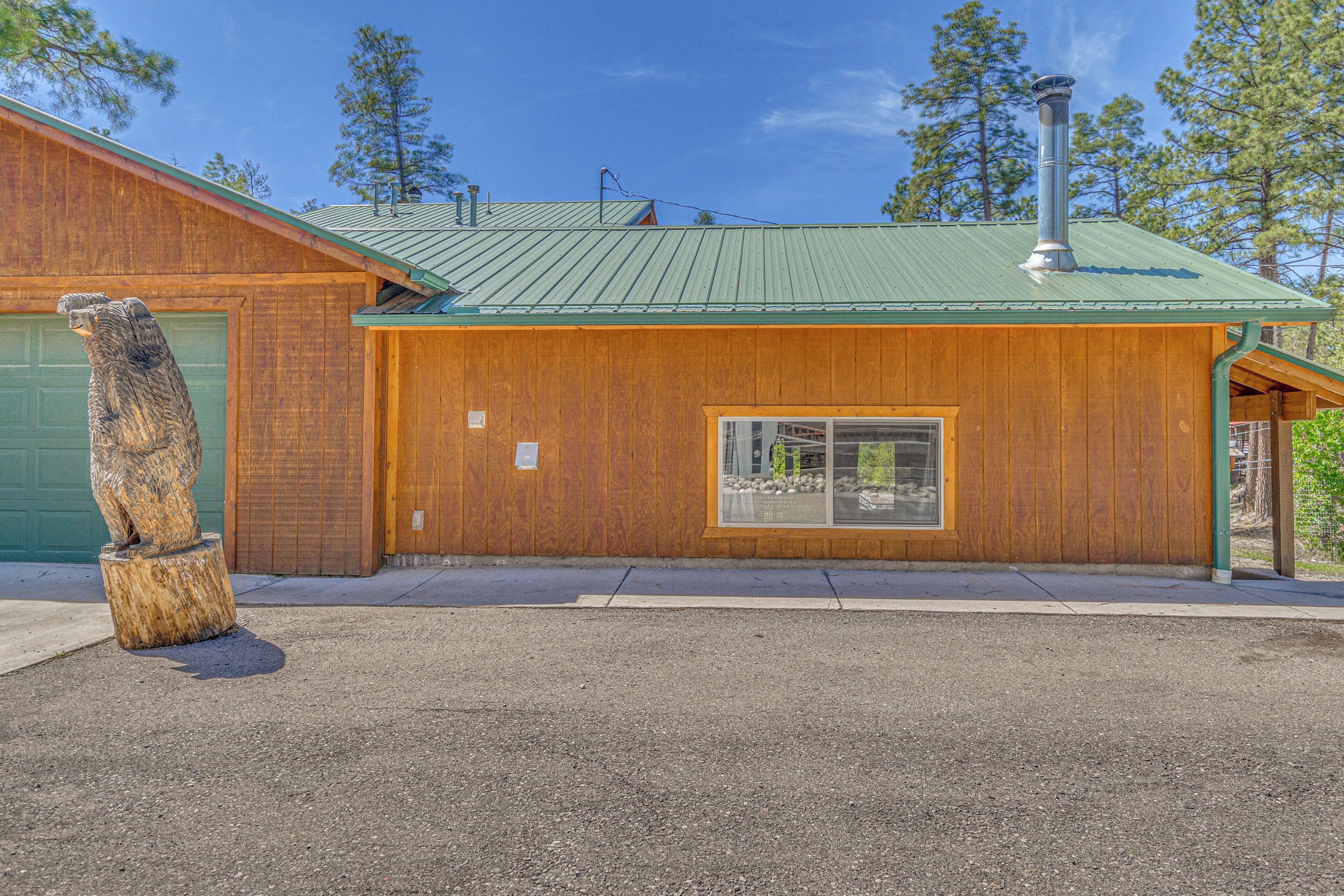 A wooden building with a green roof, a window, and a bear statue in front.