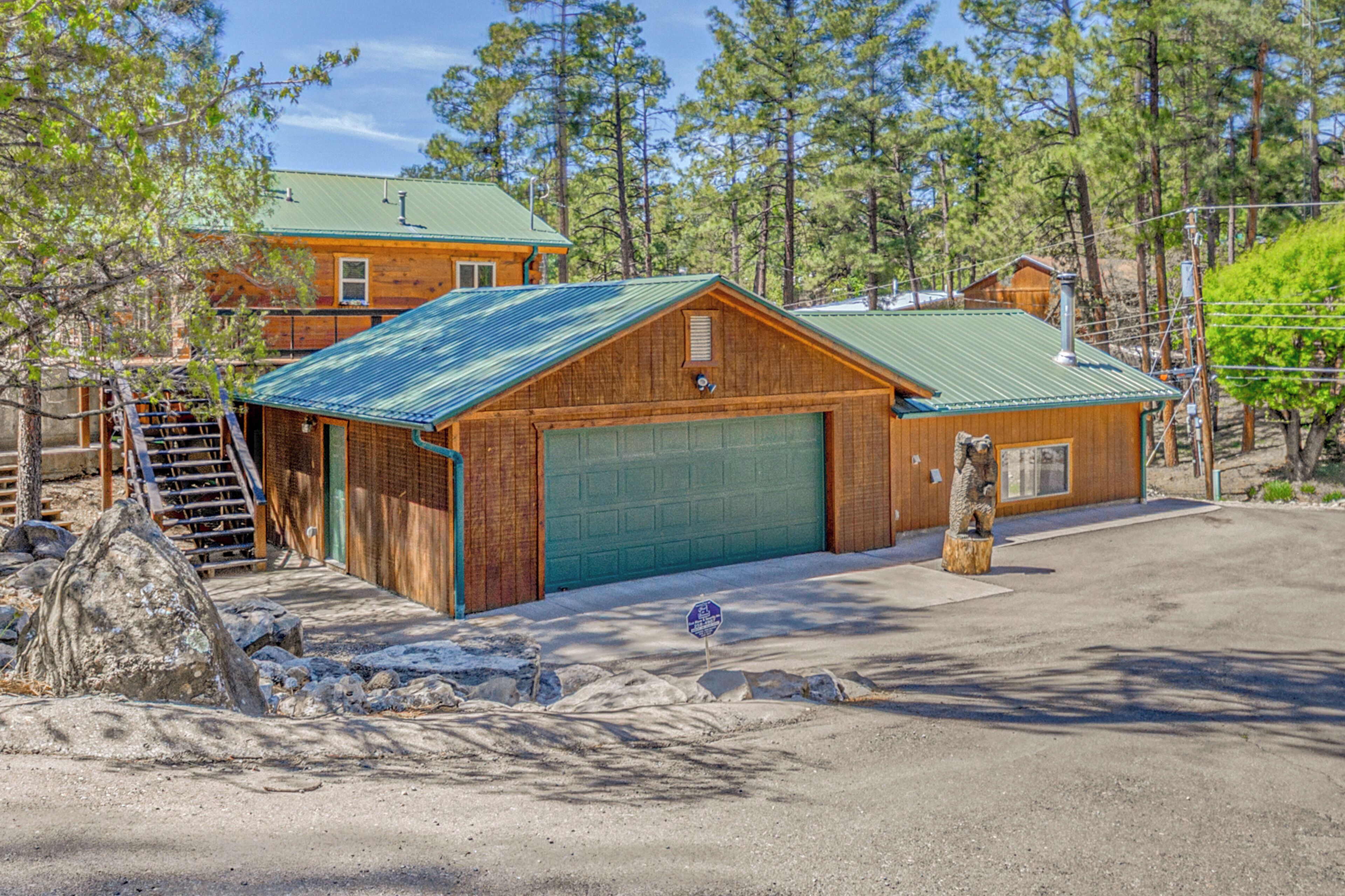 A wooden cabin with a green garage door, a wooden exterior, and a metal roof.