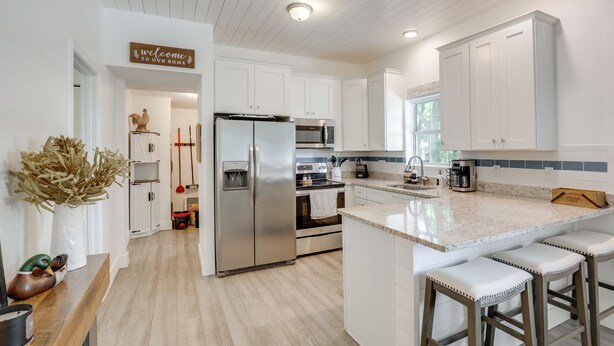 A modern kitchen with white cabinetry, stainless steel appliances, a marble countertop, and a welcome sign. - 2 Mi to Historic Dtwn St Augustine! Family Retreat (St. Augustine)