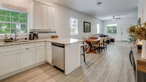 A spacious kitchen with white cabinetry, a dishwasher, and a dining area with a wooden table and chairs. - 2 Mi to Historic Dtwn St Augustine! Family Retreat (St. Augustine)