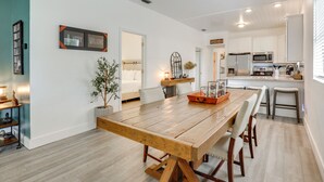 A modern kitchen with white cabinets, a wooden dining table, and a built-in microwave. - 2 Mi to Historic Dtwn St Augustine! Family Retreat (St. Augustine)