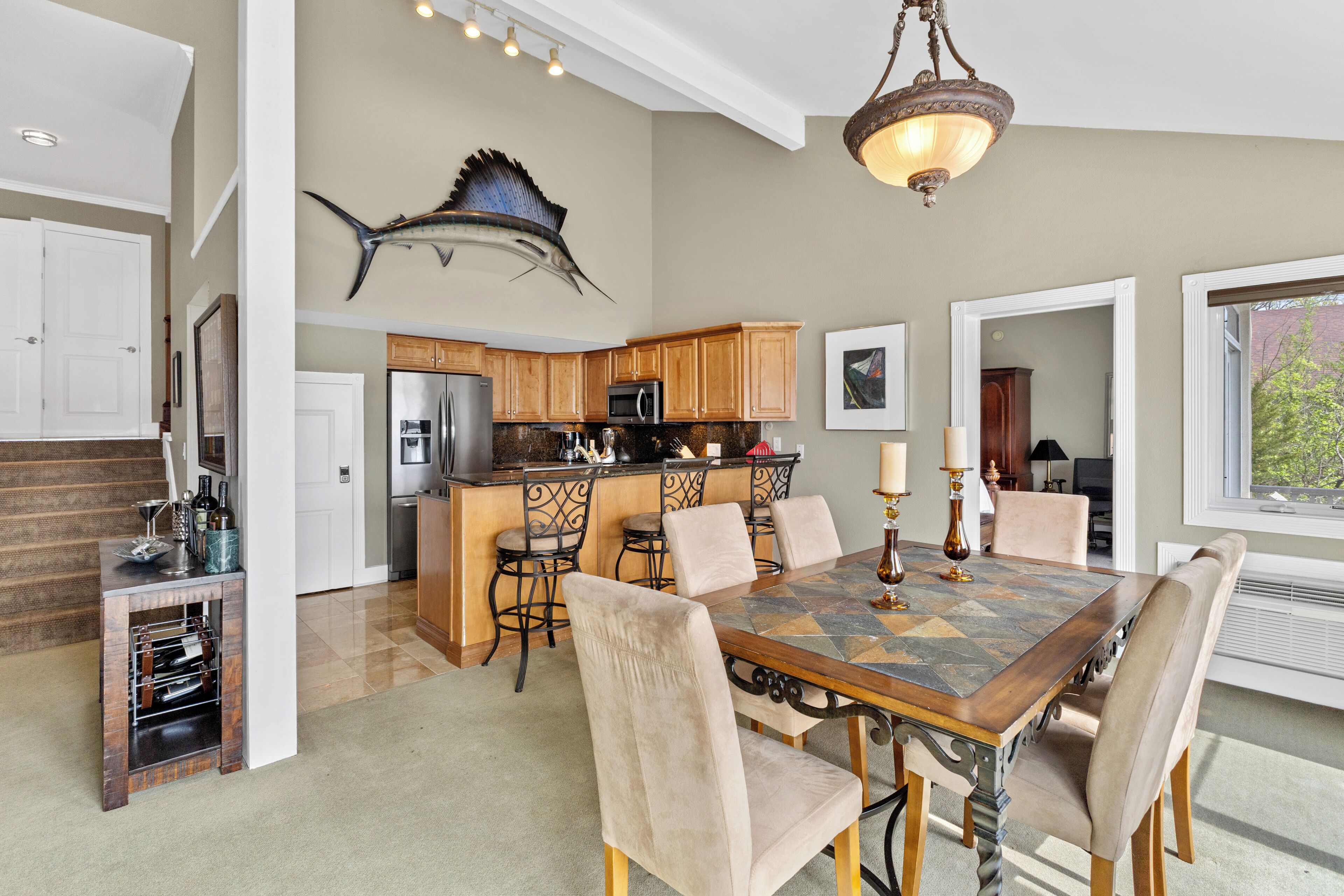 A spacious dining area with a large wooden table, comfortable chairs, and a kitchen in the background.