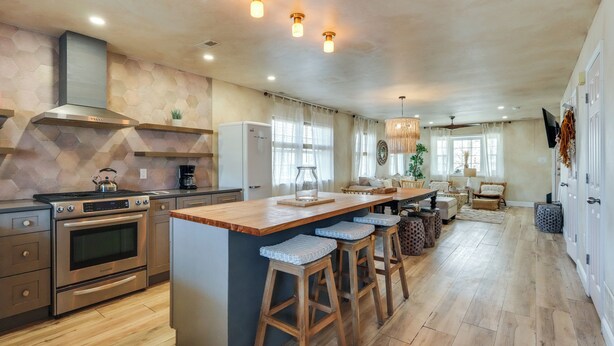 A spacious kitchen with a central island, bar stools, a built-in oven, and a large window.