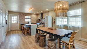 A spacious kitchen with a wooden table, bar stools, and a hanging light fixture.