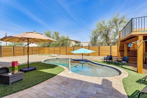 Ein Garten mit Schwimmbecken, Terrassenmöbeln und einer Holzterrasse.