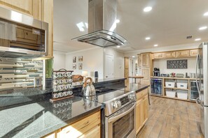 A modern kitchen with a stainless steel range hood, a built-in oven, and a black countertop. - Outdoor Entertainment Area! Lake Havasu City Home (Lake Havasu City)