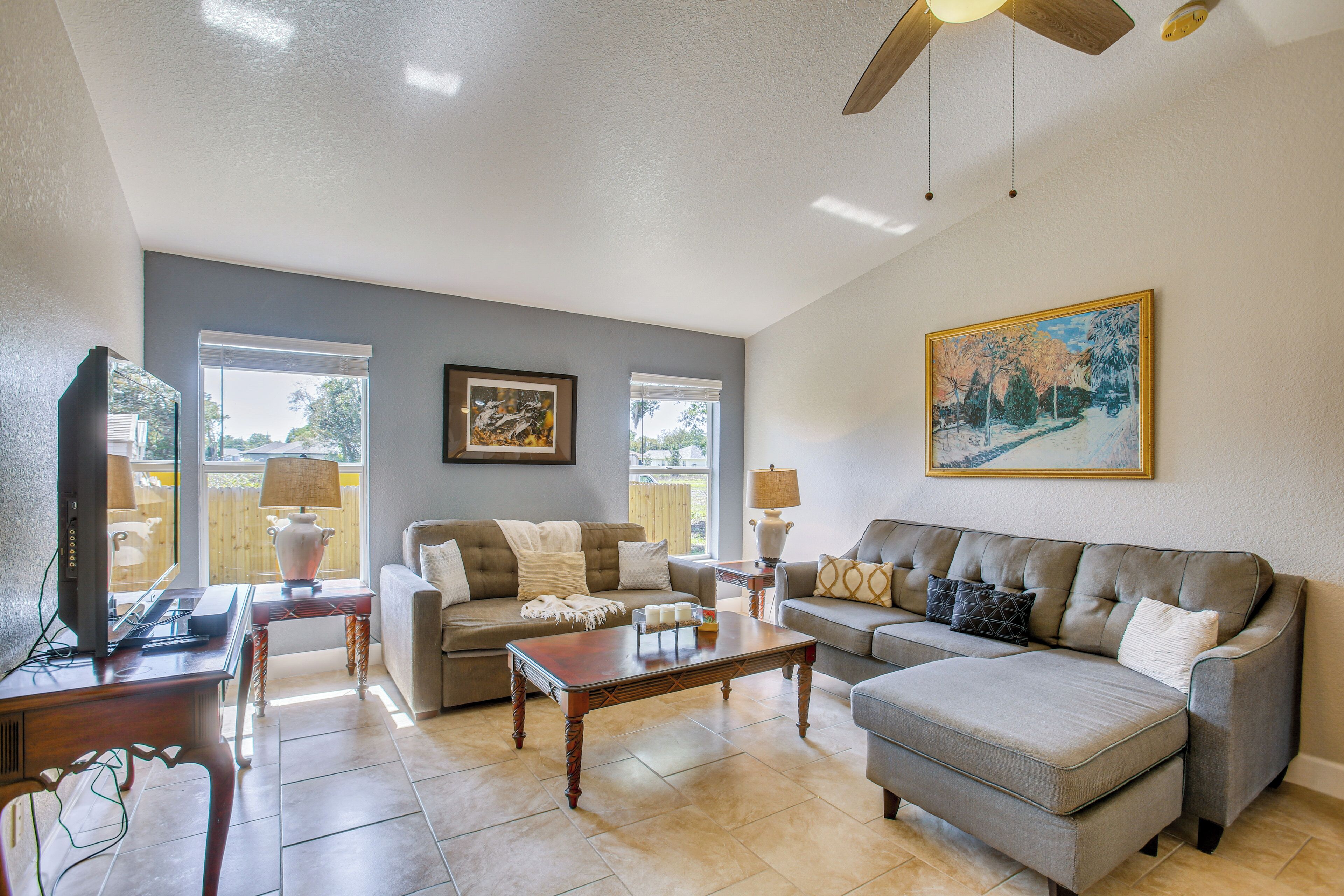 A living room with a sofa, a coffee table, a television, and a ceiling fan.