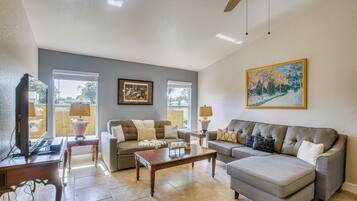 A living room with a sofa, a coffee table, a television, and a ceiling fan.