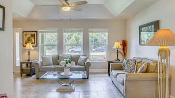 A living room with two sofas, a coffee table, a floor lamp, and a ceiling fan.