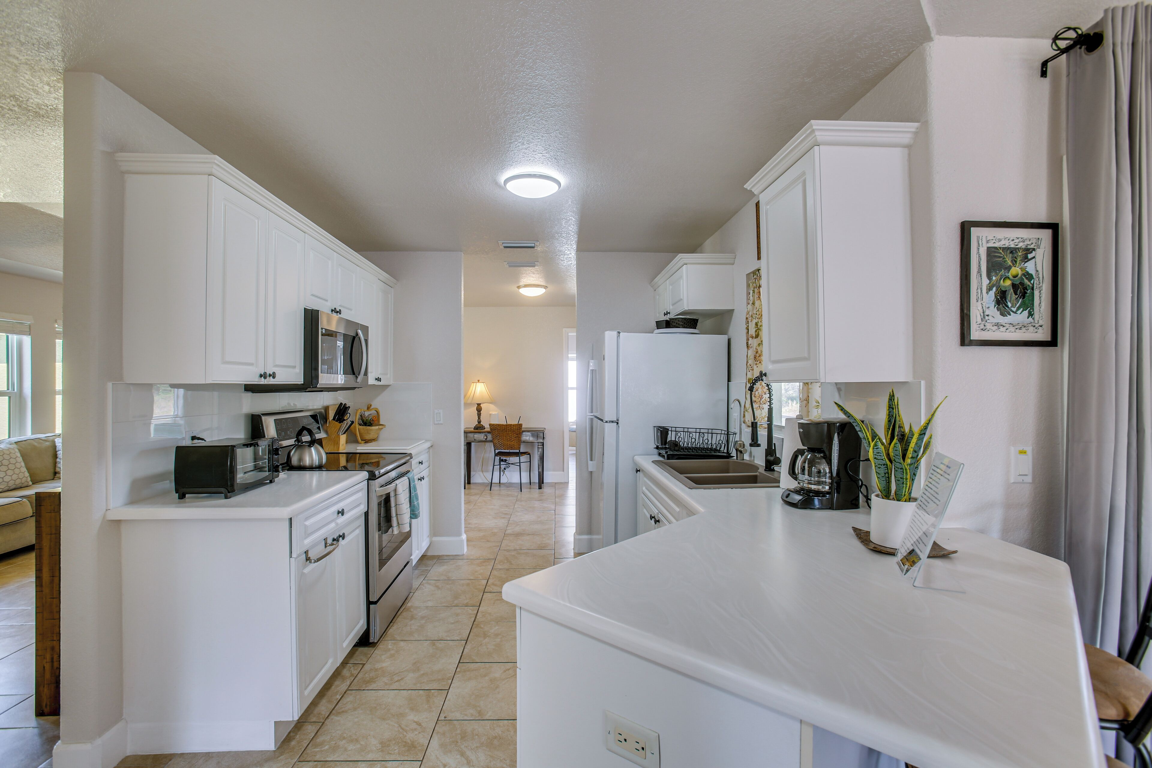 Una cocina moderna con armarios blancos, una isla central y un área de comedor al fondo.