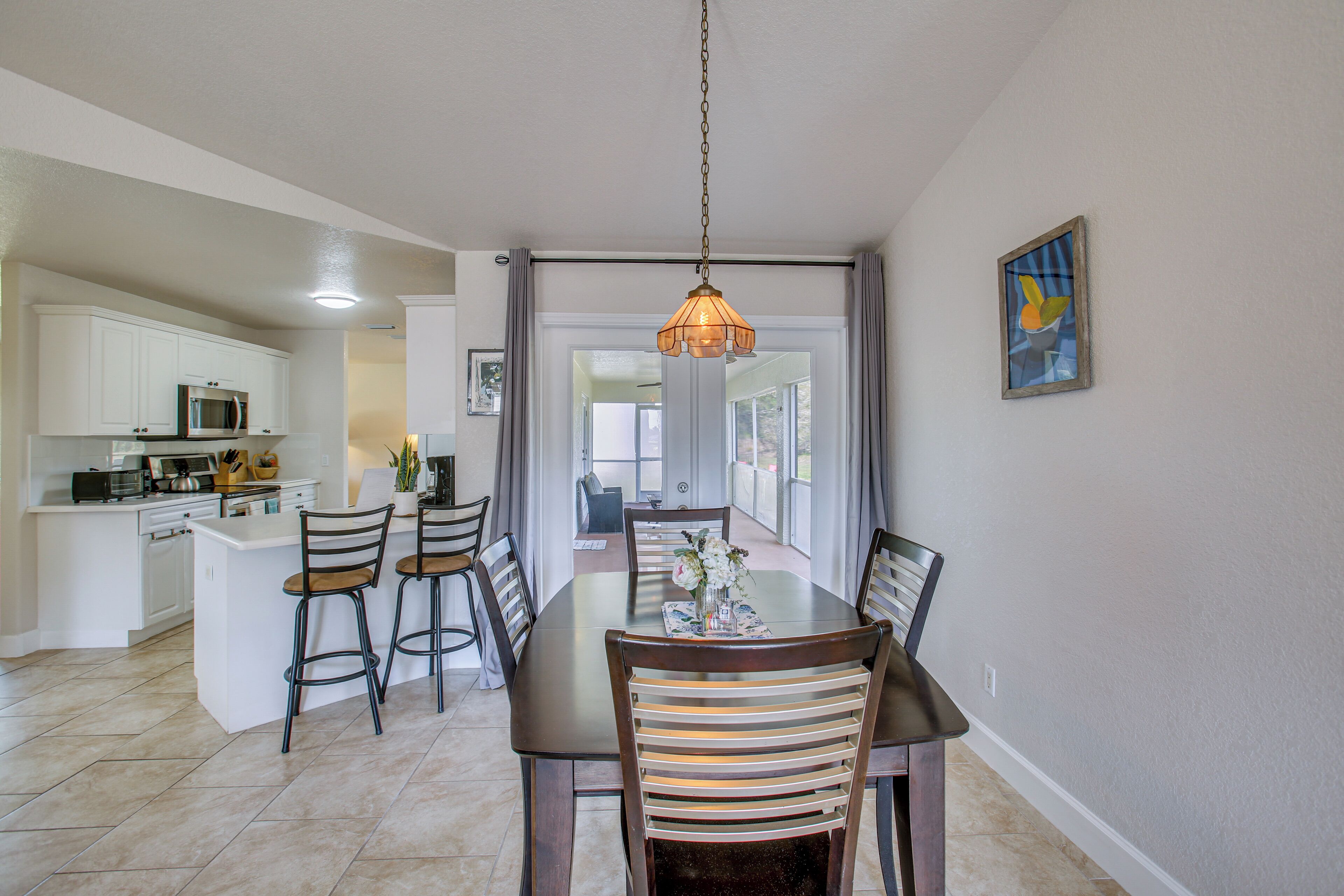 A dining area with a table, chairs, and a hanging light fixture.