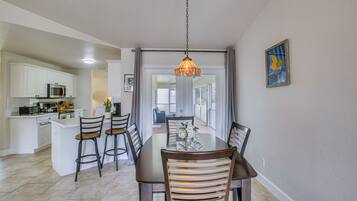 A dining area with a table, chairs, and a hanging light fixture.