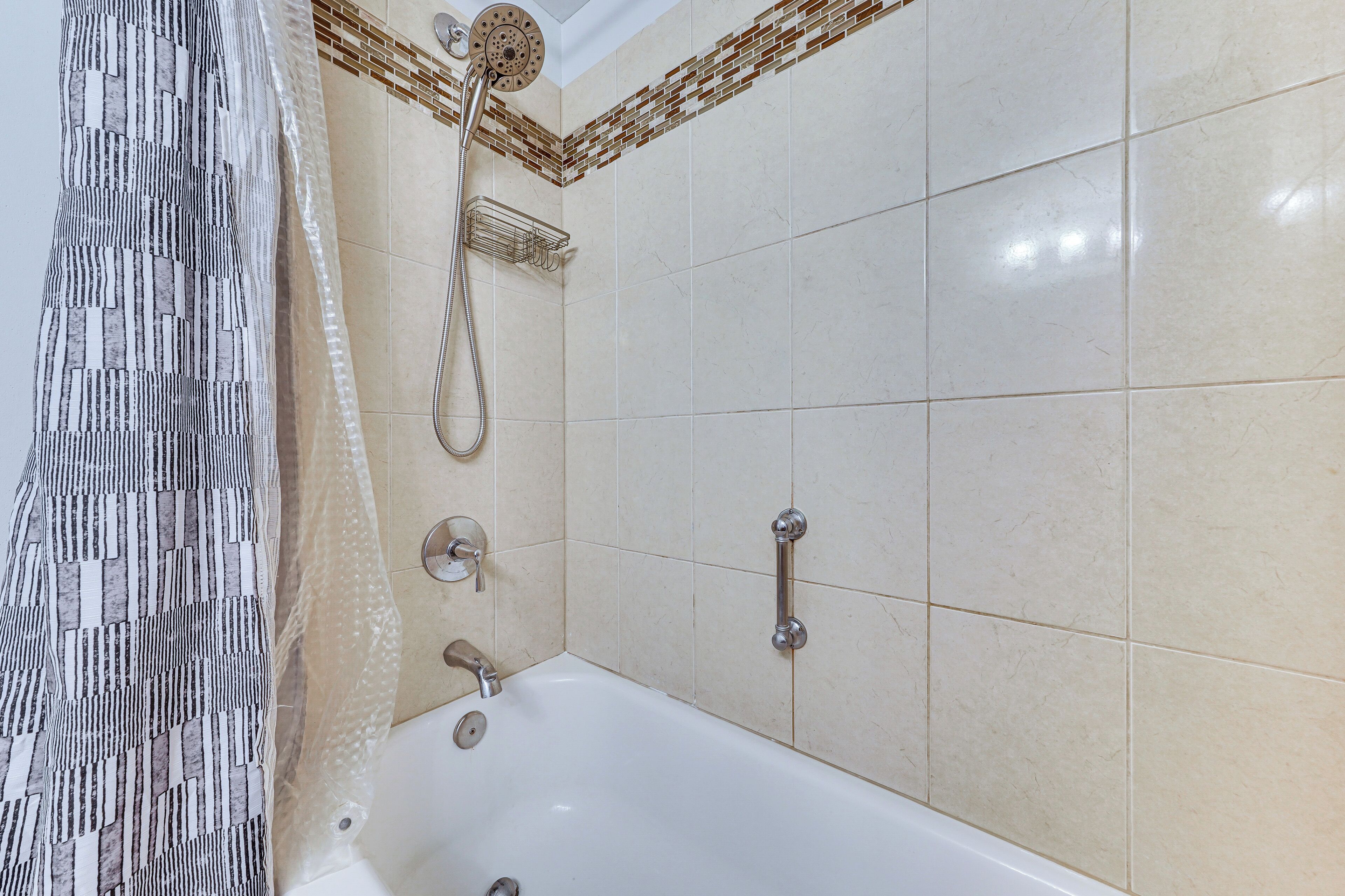 A bathroom with a bathtub, shower, and tiled walls.