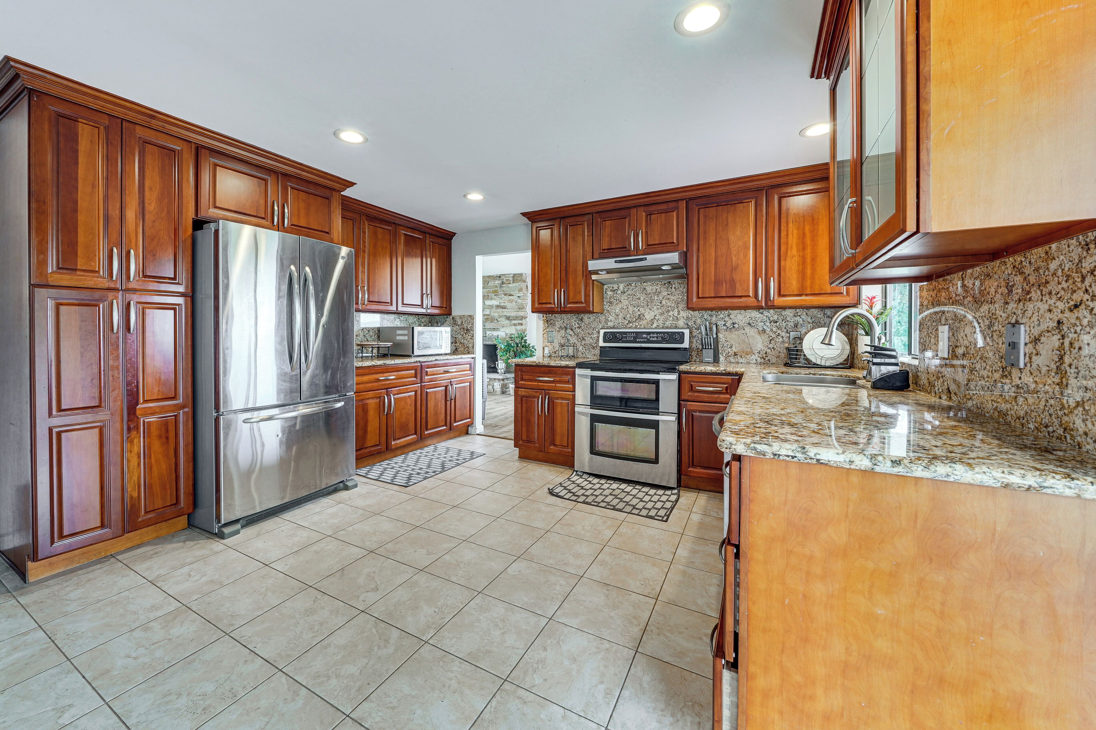 A kitchen with wooden cabinets, stainless steel appliances, granite countertops, and a stone backsplash.