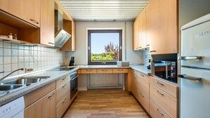 Eine moderne Küche mit Holzausstattung, einem Einbauofen und einem Fenster mit Blick auf Grünflächen.