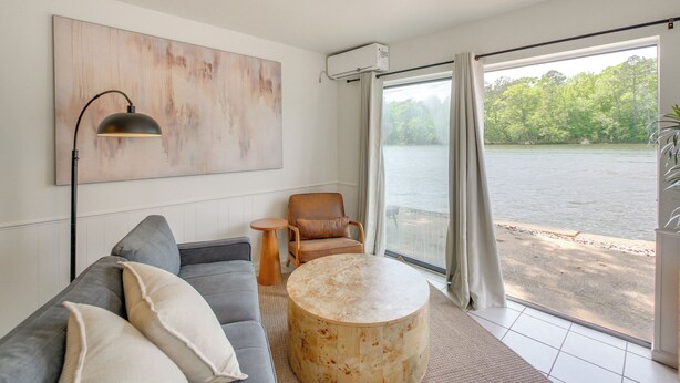A modern living room with a gray sofa, a round coffee table, a leather armchair, and a large abstract painting. - Waterfront Couples Retreat in Hot Springs! (Hot Springs)