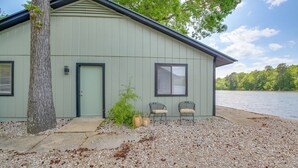 A building with a door, two windows, and a bench outside. - Waterfront Couples Retreat in Hot Springs! (Hot Springs)