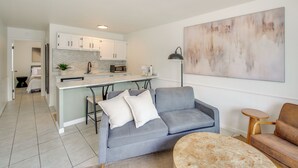 A modern living room with a grey sofa, a round coffee table, and a kitchen in the background. - Waterfront Couples Retreat in Hot Springs! (Hot Springs)