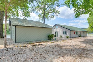 A building with a metal roof, a gravel driveway, and a small bush in front.