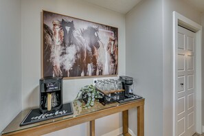 A coffee station with two espresso machines, a glass display case, and a framed artwork above. - Fishing & Creek On-site! Red Lodge Family Retreat (Red Lodge)