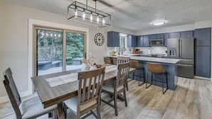 Una cucina moderna con mobili scuri, un'isola centrale e un'area pranzo con sedie e tavolo in legno.