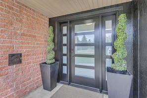 A black-framed door with frosted glass panels, flanked by two large black planters with green plants. - Fishing & Creek On-site! Red Lodge Family Retreat (Red Lodge)
