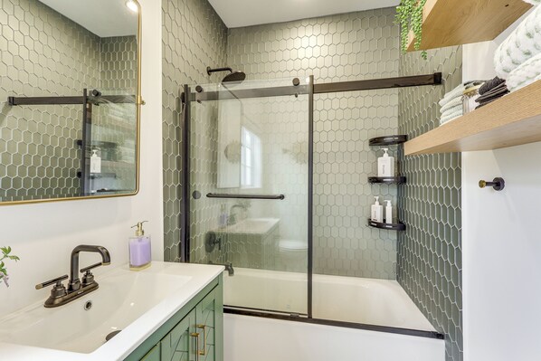 A modern bathroom with a glass-enclosed shower, a white sink, and a mirror.