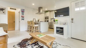 A modern kitchen with white cabinets, a central island, and a flat-screen TV above the counter.