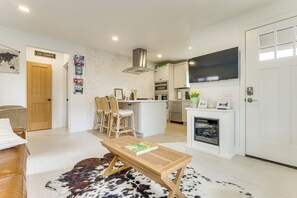 A modern kitchen with white cabinets, a central island, and a flat-screen TV above the counter. - Shop, Dine, Walk to Ocean! San Clemente Retreat (San Clemente)