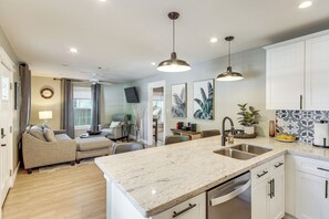 A modern kitchen with a marble countertop, white cabinets, and pendant lighting. - Walk to Beach, Dining & Aquarium: Gulfport Home! (Gulfport)
