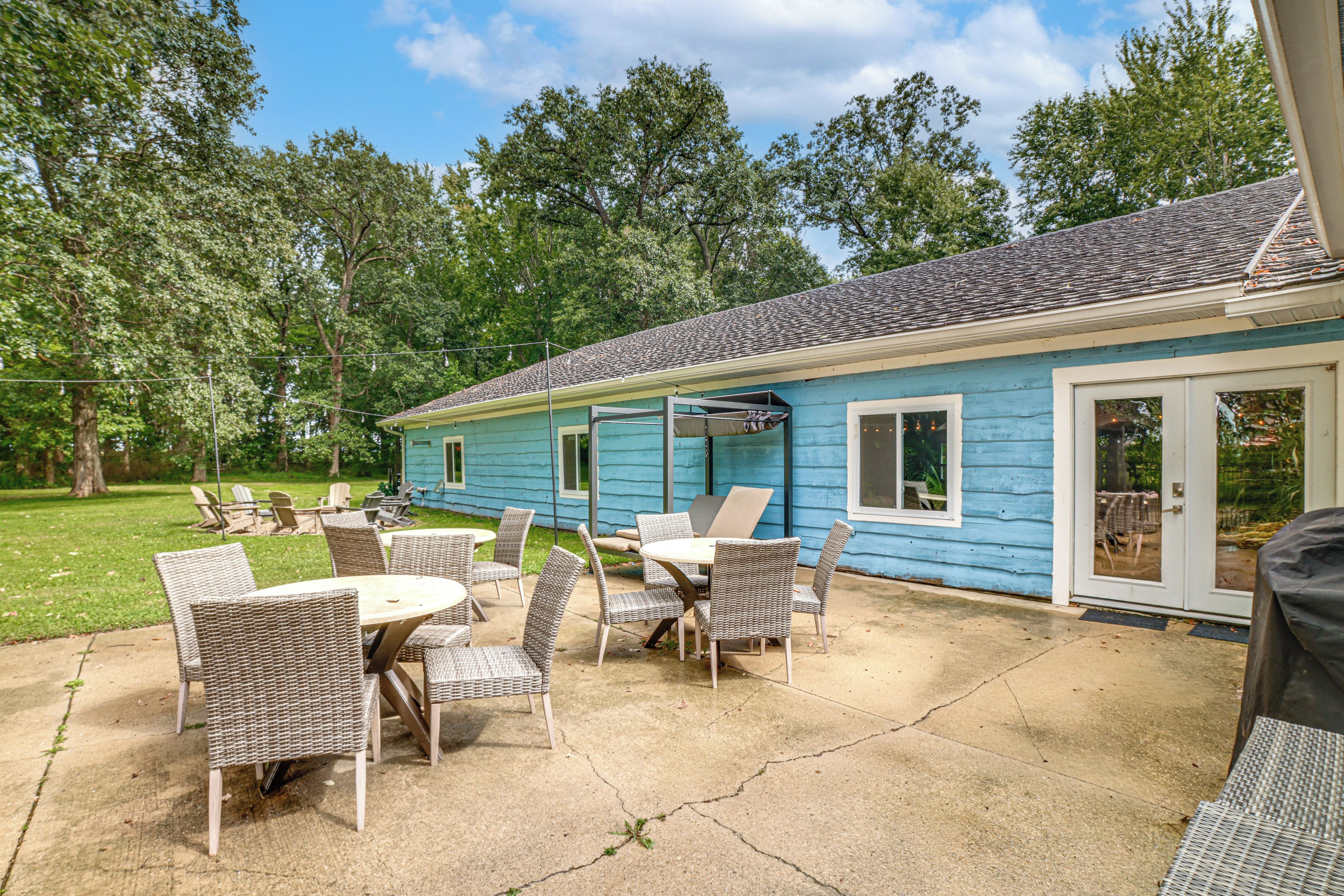 A blue house with a patio area featuring wicker furniture and a concrete floor.