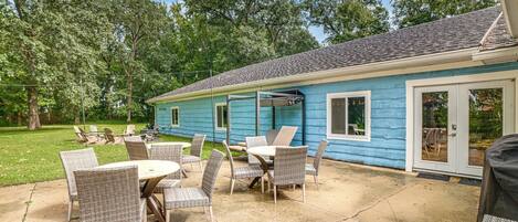 A blue house with a patio area featuring wicker furniture and a concrete floor.