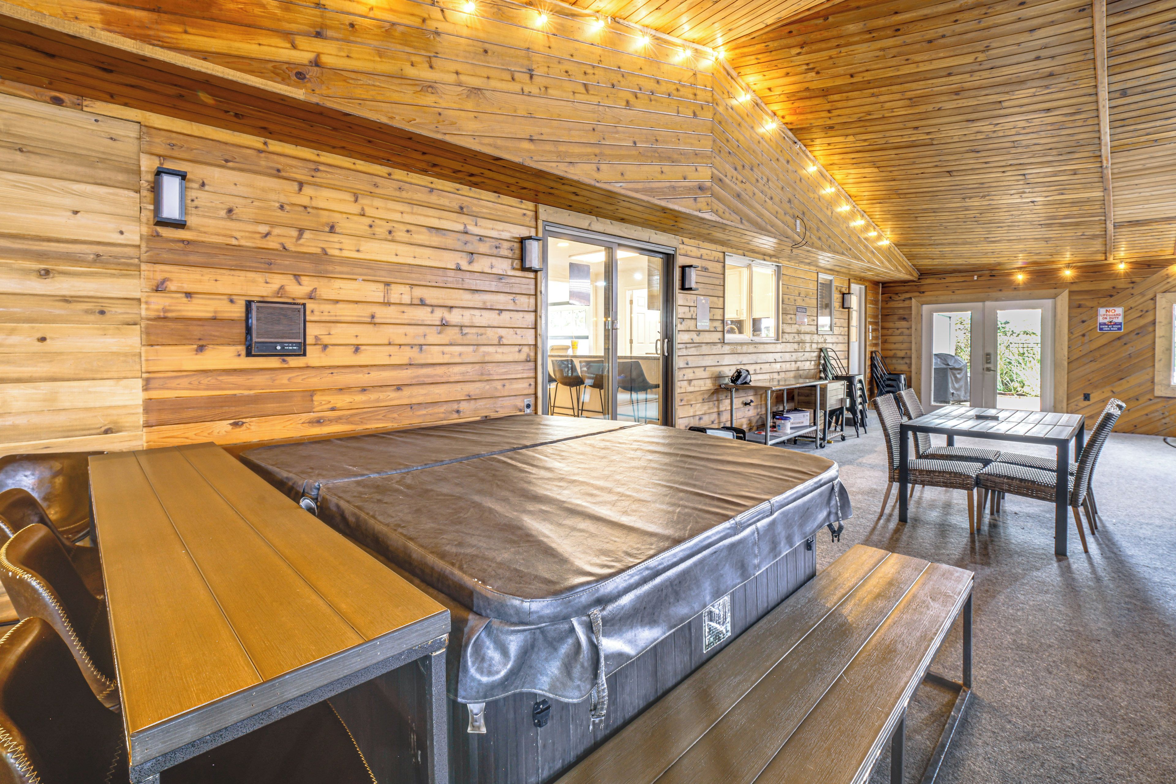 A wooden interior with a massage table, a dining area, and a view of the outdoors.