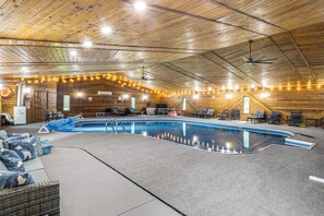 An indoor swimming pool with a wooden ceiling, surrounded by lounge chairs and a covered seating area. - Featured on TV! Epic Indoor Pool Sleeps 24 (Bridgman)