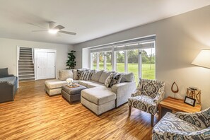 A spacious living room with a sectional sofa, ottoman, and patterned armchair. - Featured on TV! Epic Indoor Pool Sleeps 24 (Bridgman)