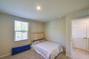 A bedroom with a bed, a window, a door, and a radiator.