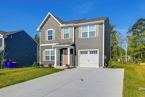 A two-story house with a garage, a front porch, and a well-maintained lawn.