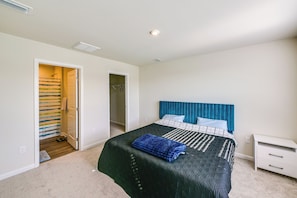 A bedroom with a bed, a nightstand, a closet, and a bathroom.