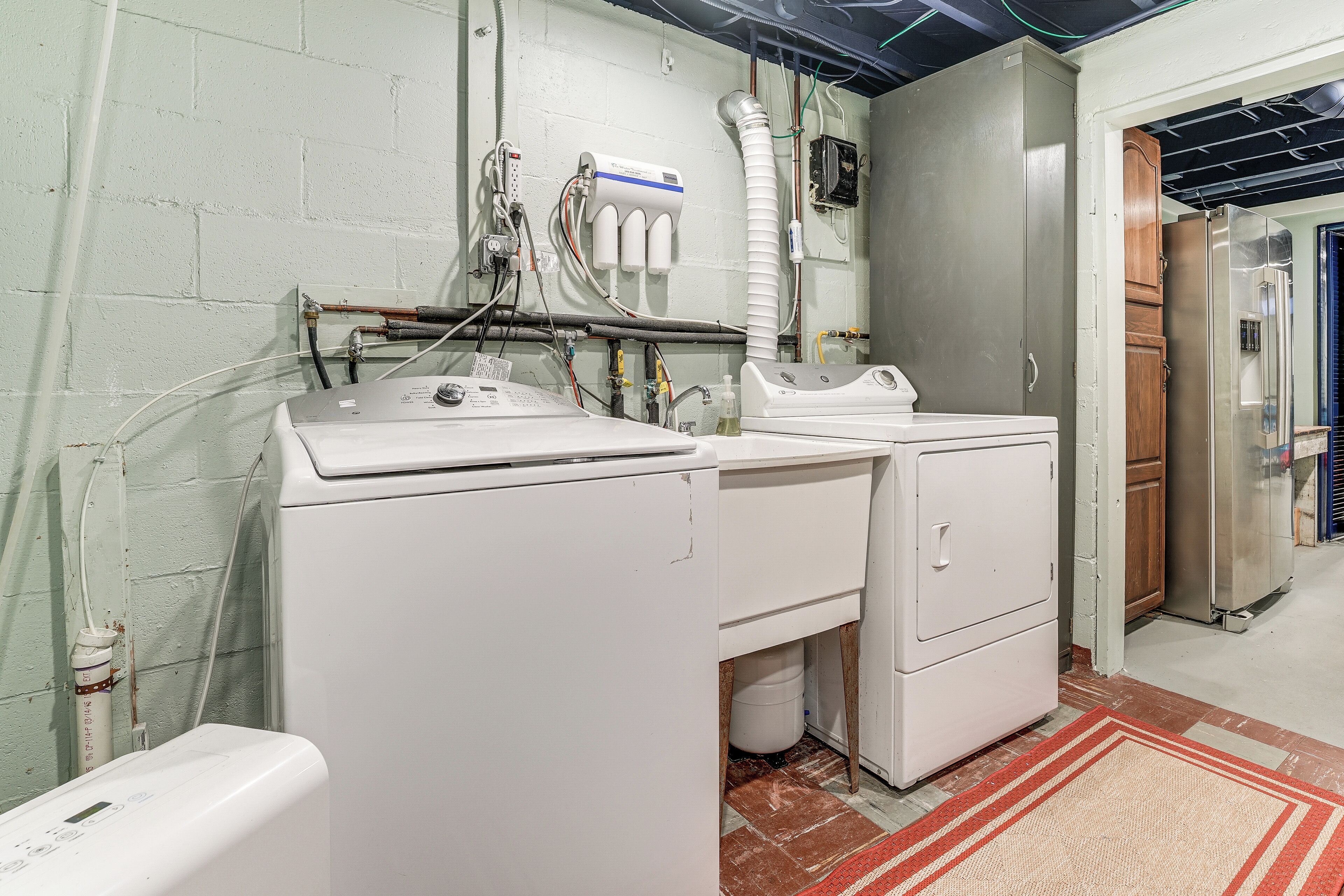A laundry room with two washing machines, a dryer, and a water heater.