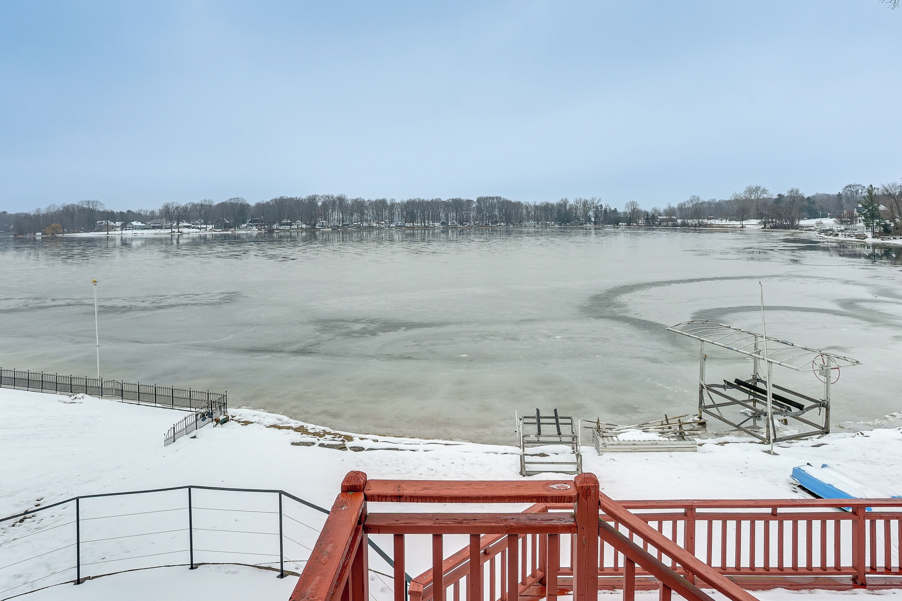 Un lago ghiacciato con un molo di legno e ringhiere metalliche in primo piano.