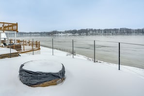 Ein mit Schnee bedeckter Balkon mit Blick auf einen gefrorenen Fluss und ferne Bäume.
