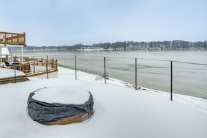 A snow-covered deck with a view of a frozen river and distant trees.